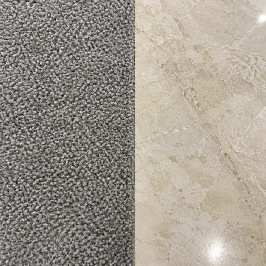 Photorealistic macro photograph comparing a patch of low-pile office carpet fibre against polished stone flooring side by side under studio light, no people and no text