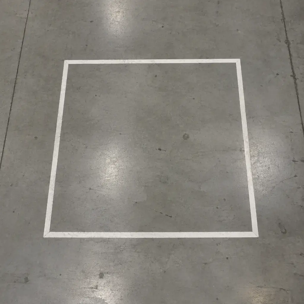 Painted white safety zone outline on a bare grey concrete floor
